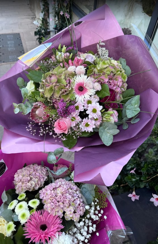 Photo de l'avis : deux bouquets emballés dans un papier violet et rose
