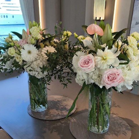 Photo de l'avis : deux vases de fleurs blanches et roses sur la table d'un yacht