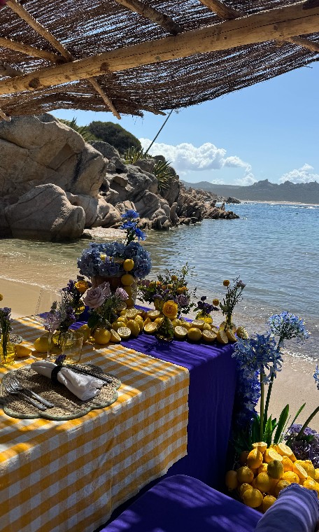 Table dressée sur une plage corse, fleurs bleues et violettes, citrons