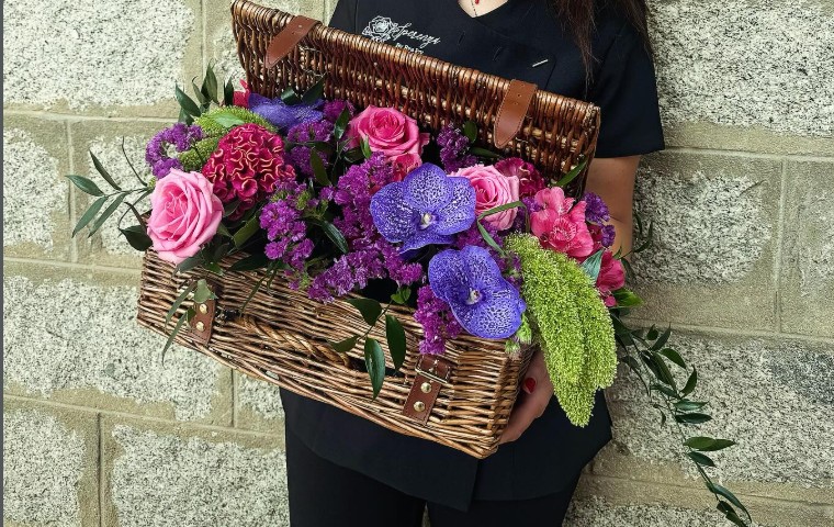 Panier en osier garni de roses, d'orchidées et de statice